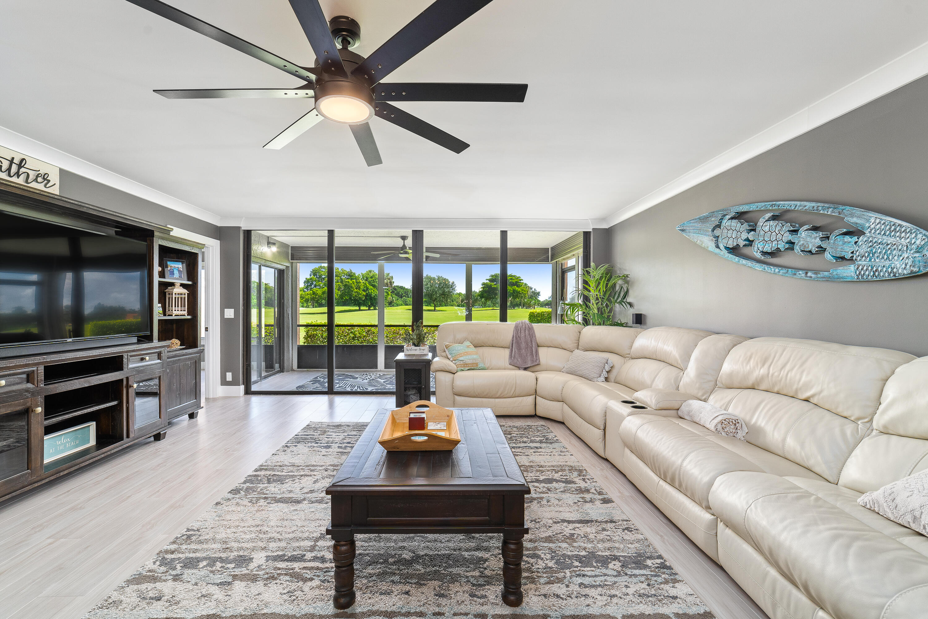 a living room with furniture a flat screen tv and a floor to ceiling window