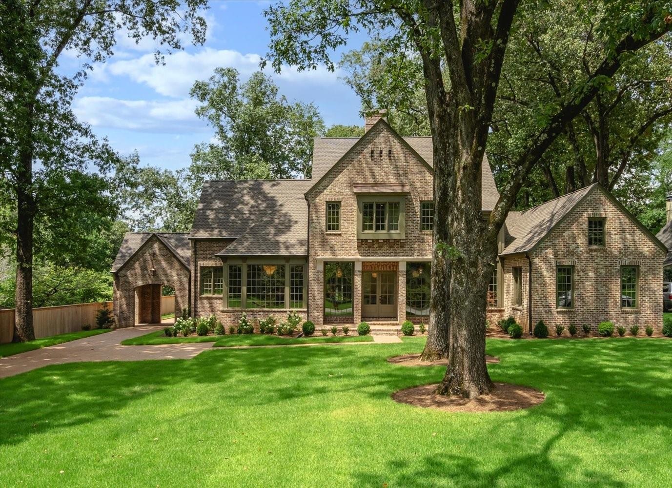 a front view of a house with a garden and trees