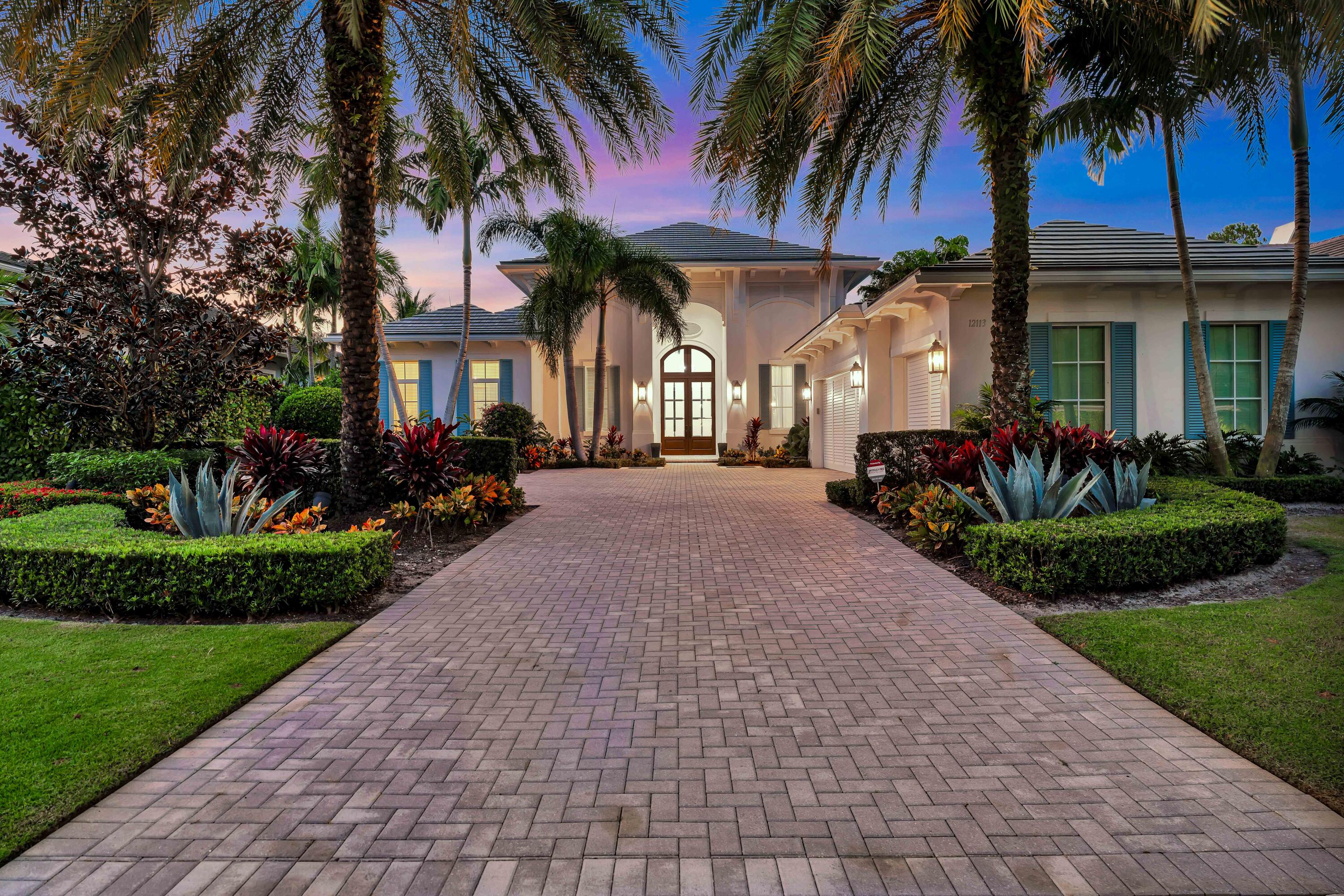 a front view of a house with a yard and potted plants