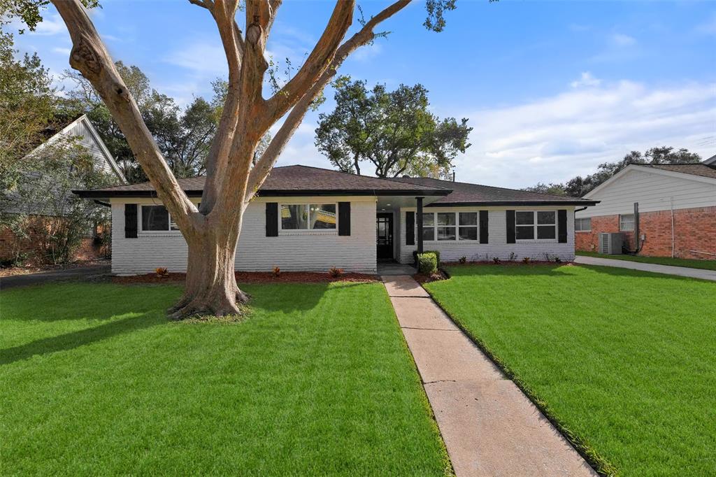 a view of house in front of a big yard with large trees