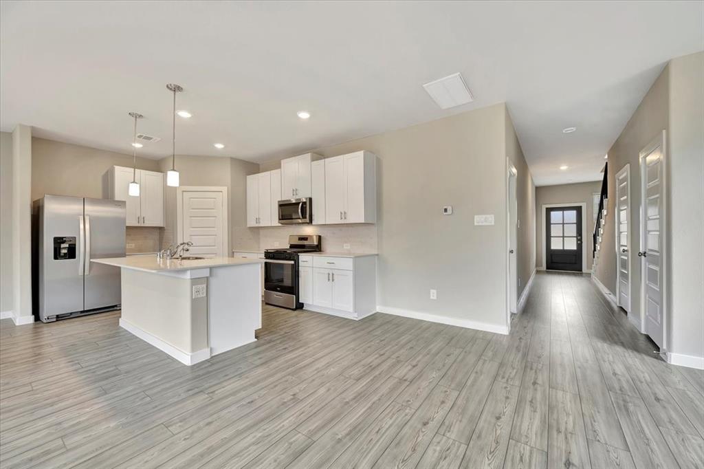 a view of kitchen with cabinets wooden floor and stainless steel appliances