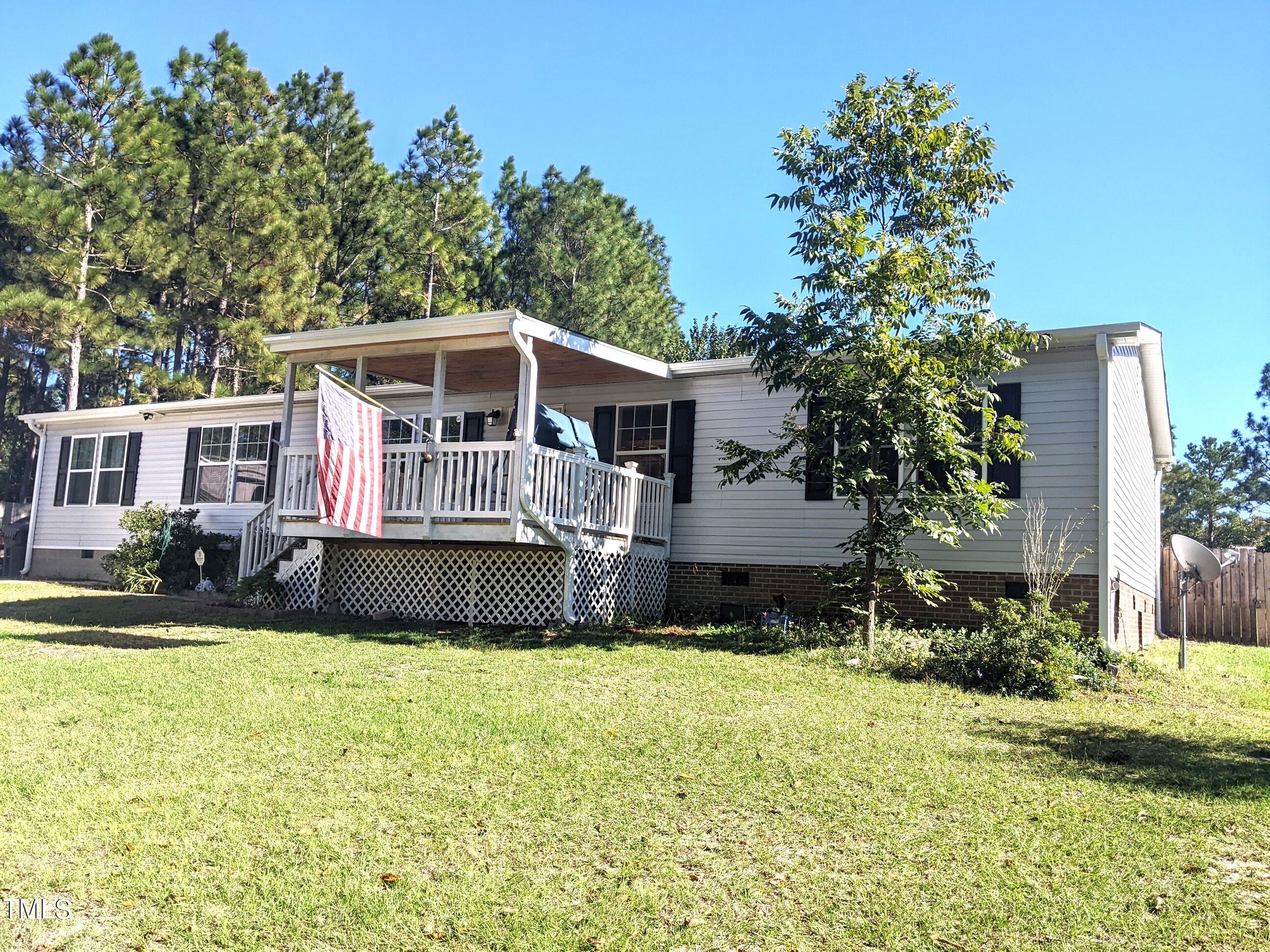 a view of house with yard and trees in the background