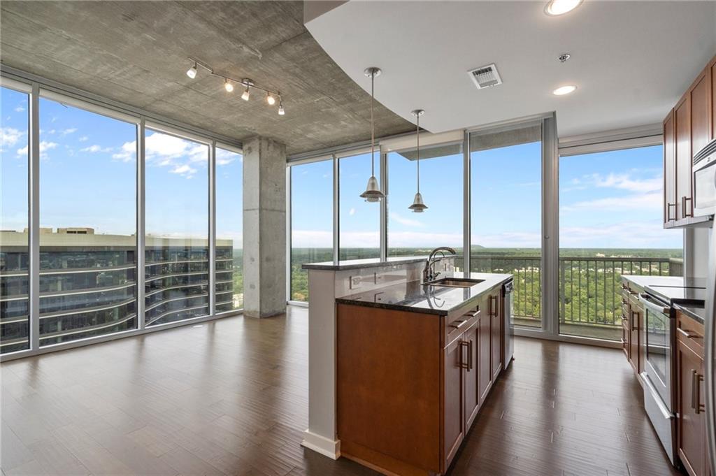 a open kitchen with kitchen island granite countertop a large window and a counter space