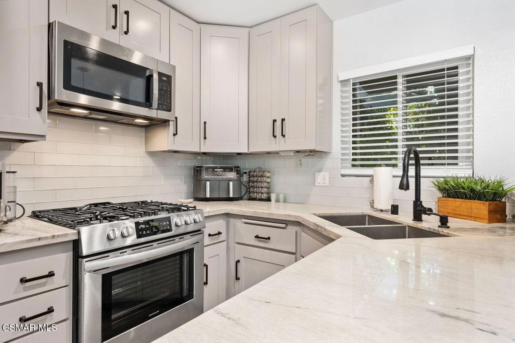 a kitchen with stainless steel appliances a stove microwave and sink