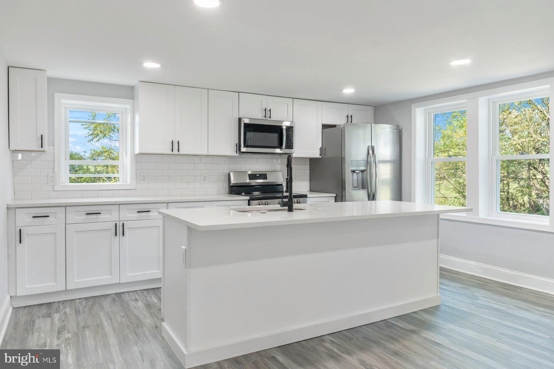 a kitchen with kitchen island white cabinets and sink