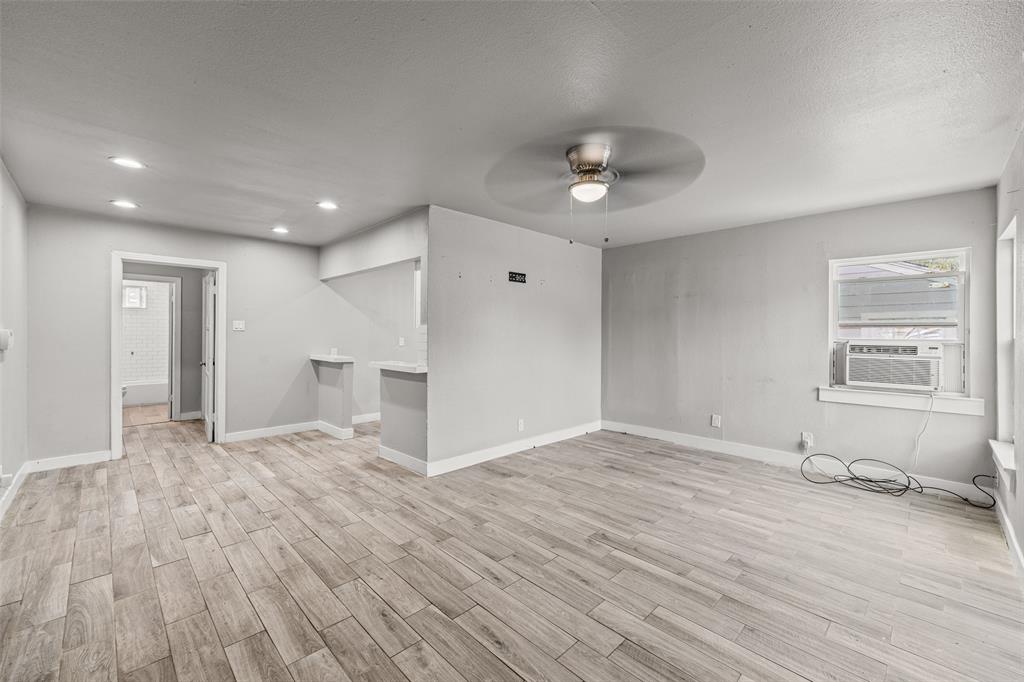 a view of an empty room with a window and wooden floor