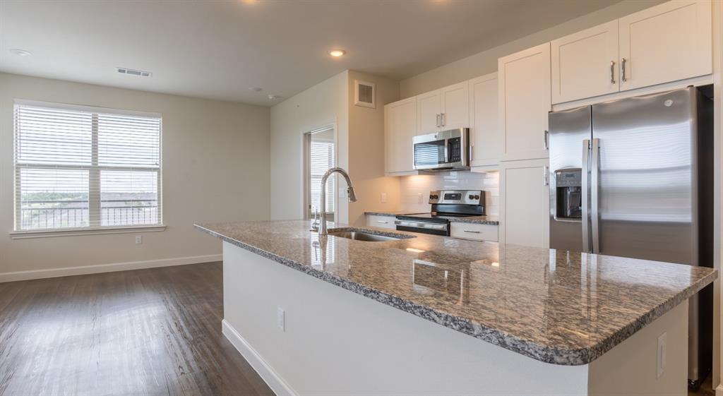 a kitchen with kitchen island a counter top space a sink and stainless steel appliances