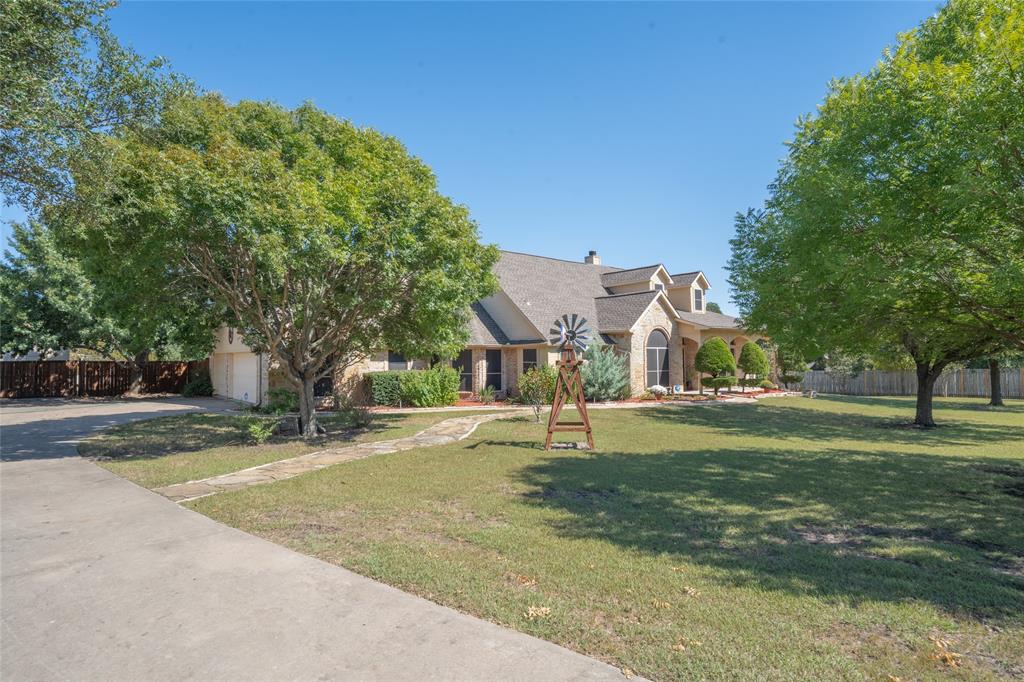 a view of a big house with a big yard and large trees