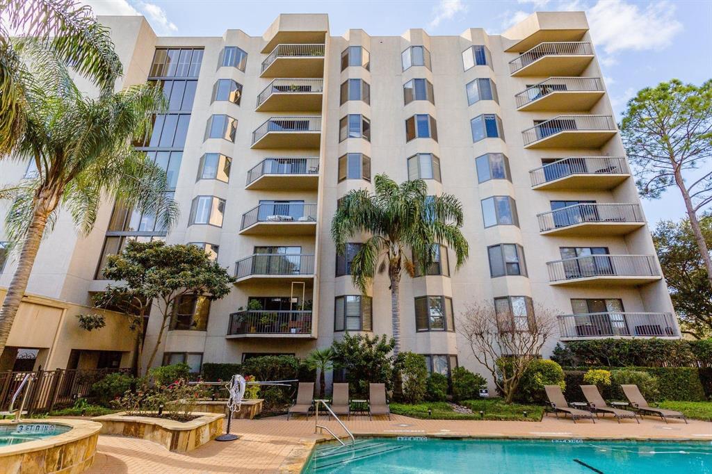 a front view of multi story residential apartment building with yard and parking space