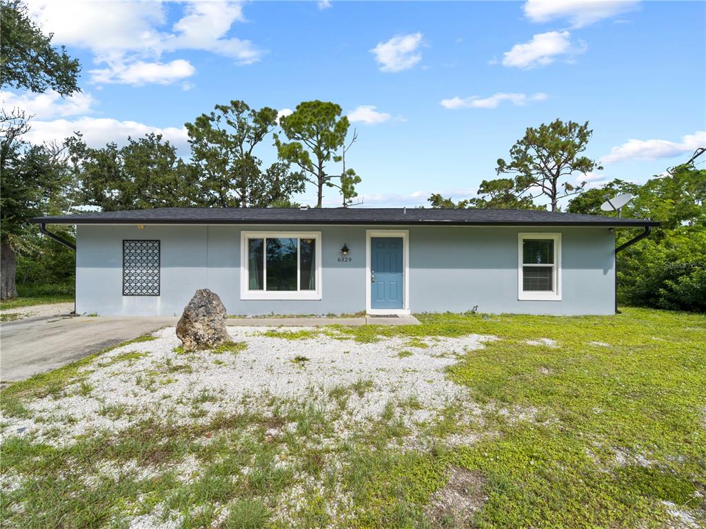 a front view of house with yard and trees around