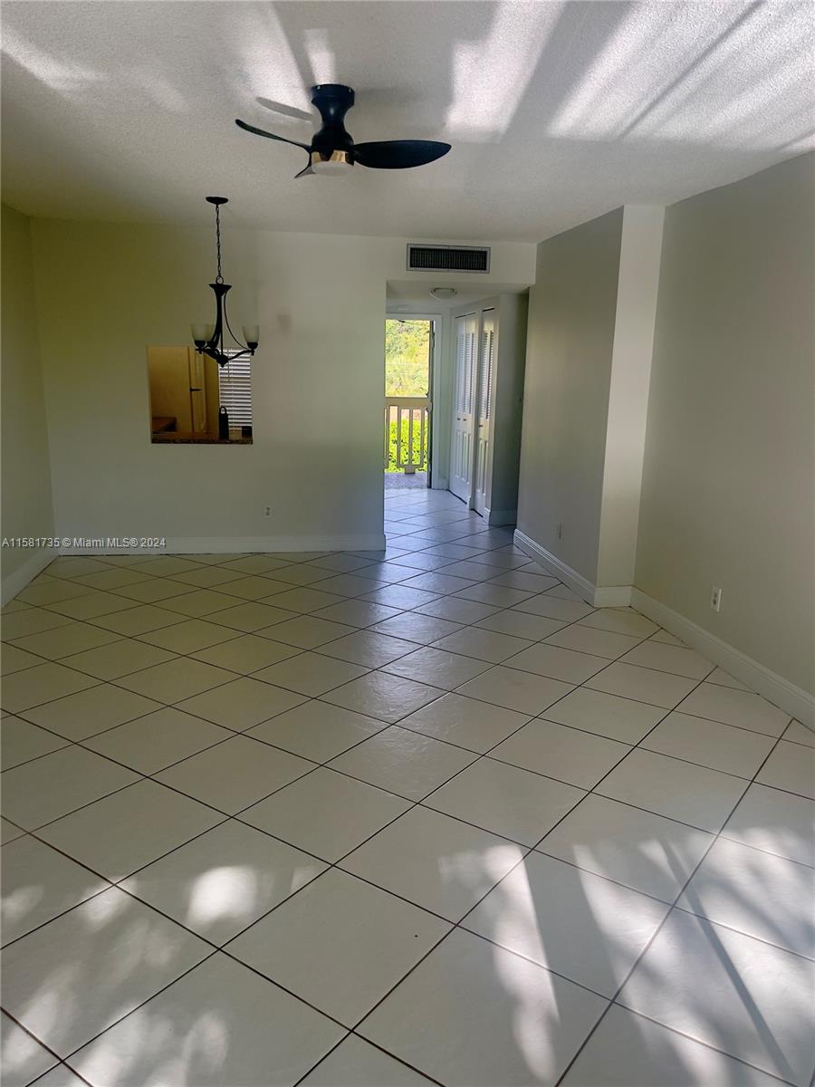 an empty room with windows and ceiling fan