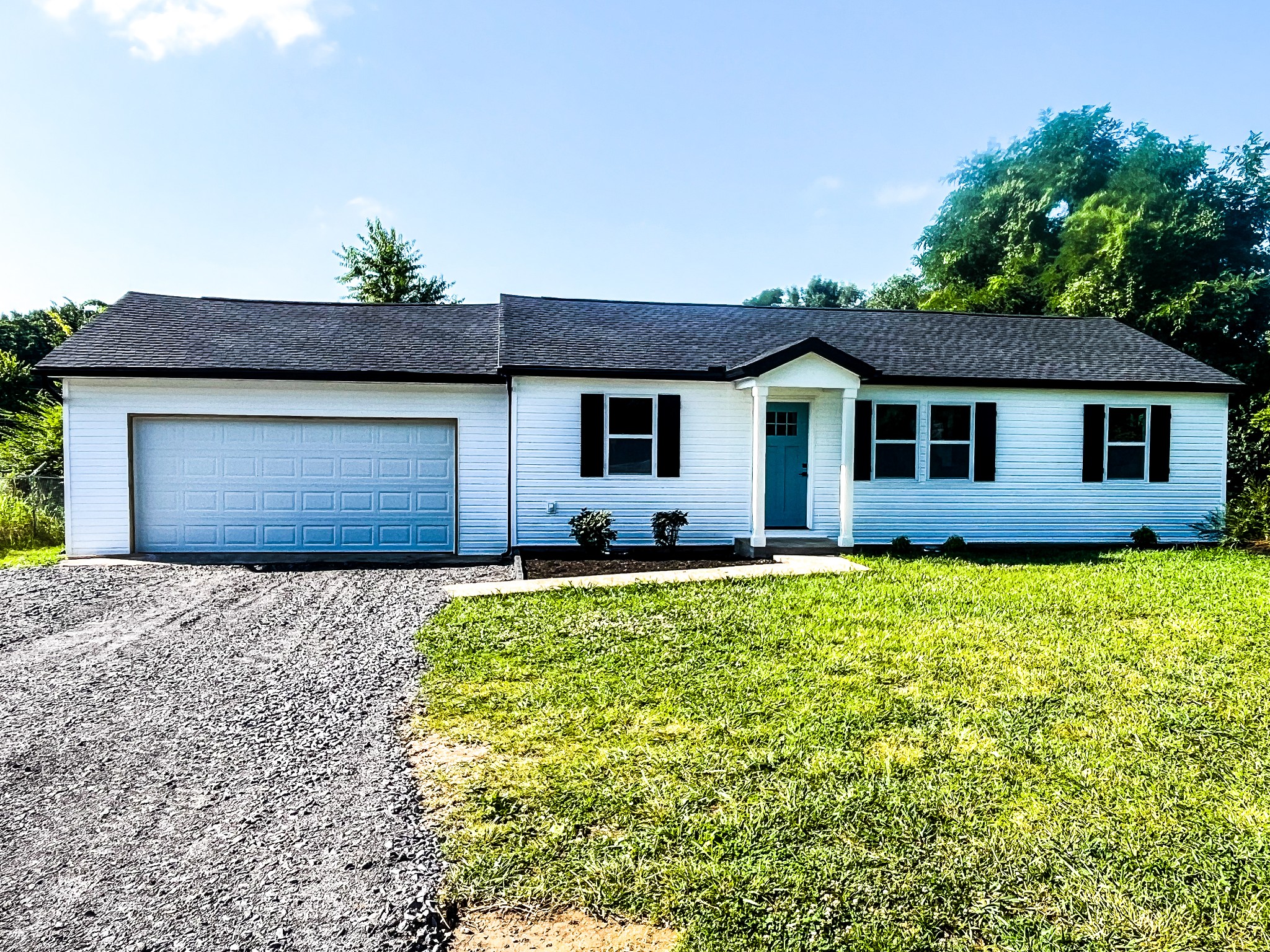 a front view of house with yard and trees in the background