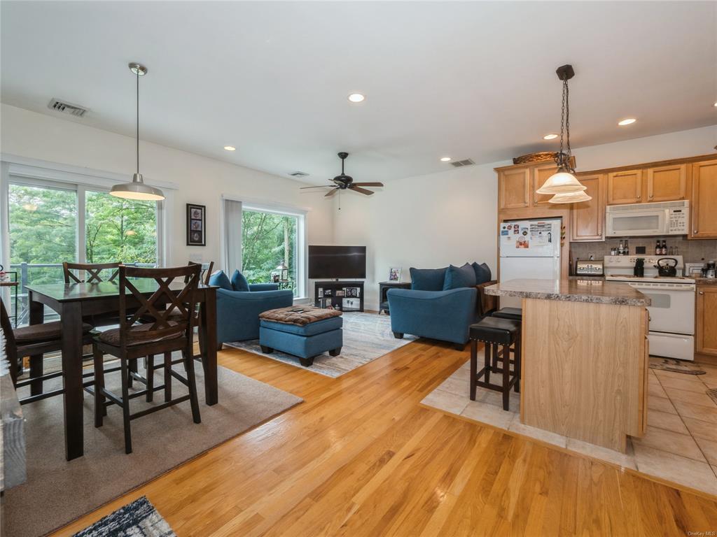 Kitchen featuring a center island, backsplash, light hardwood / wood-style floors, decorative light fixtures, and white appliances