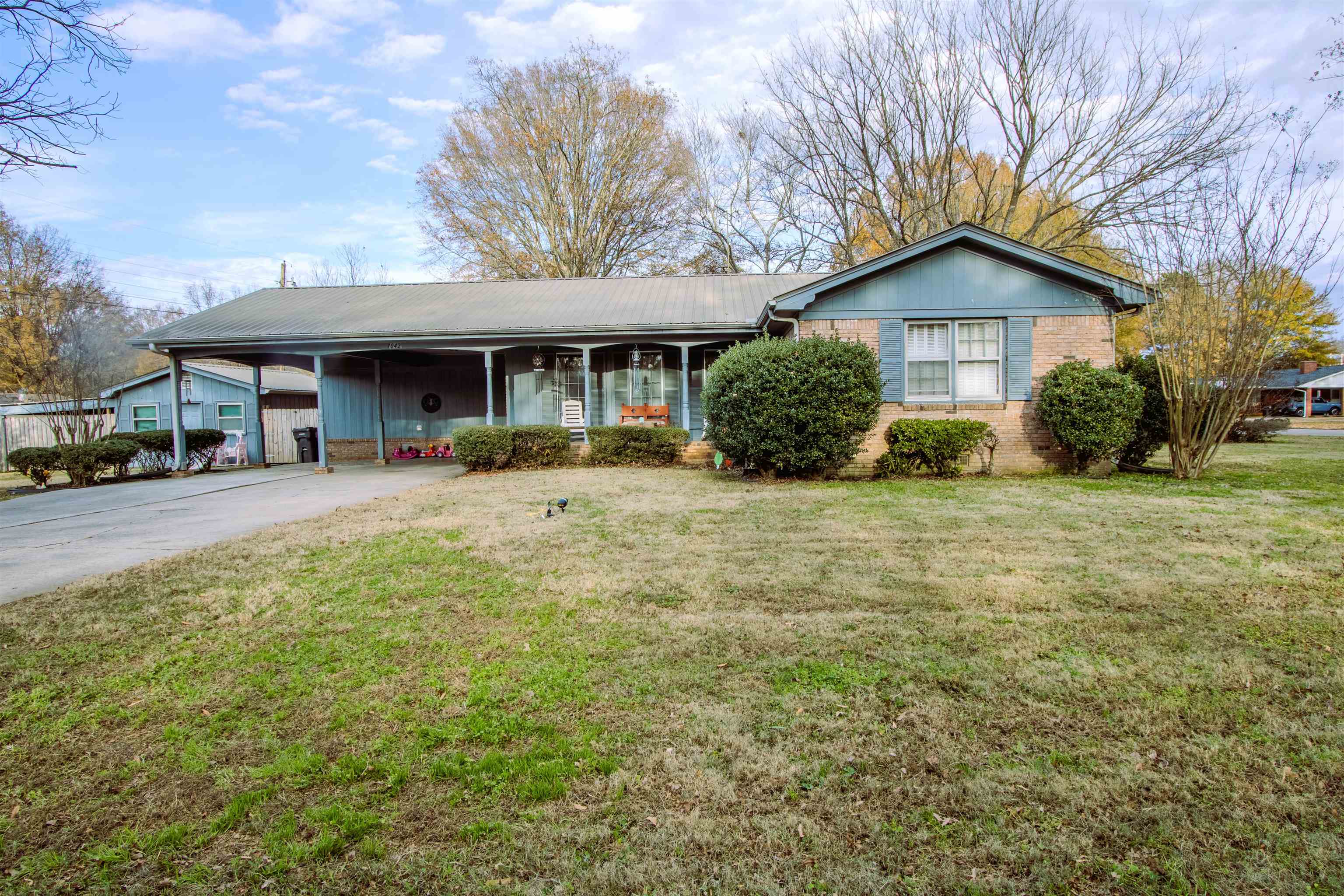 Single story home featuring a front lawn and a carport