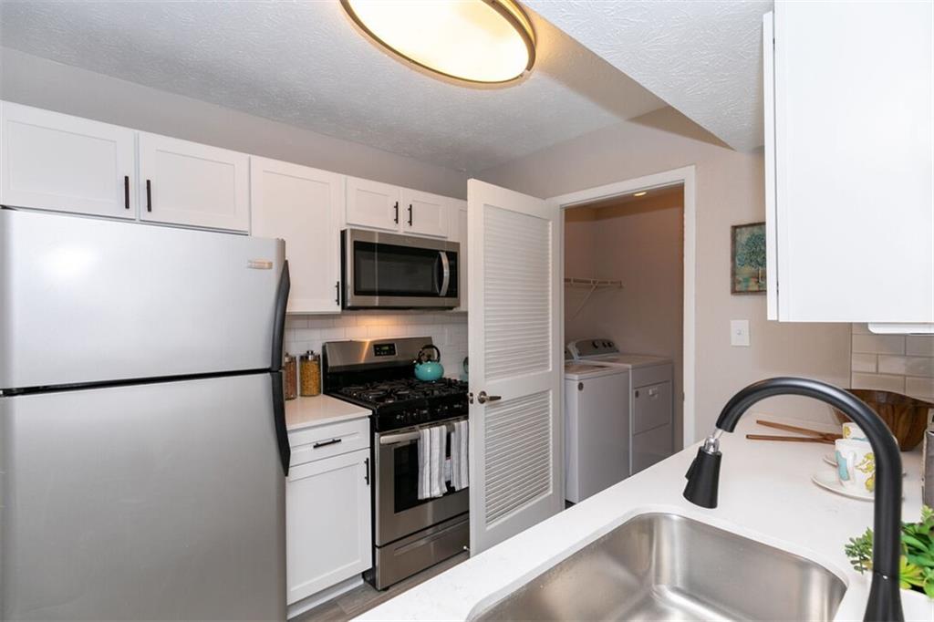 a kitchen with stainless steel appliances kitchen island a refrigerator sink and white cabinets