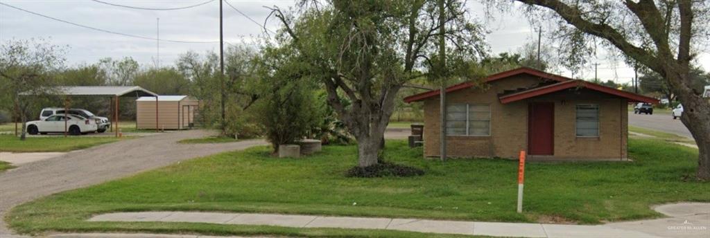 a view of a wooden house with a yard and large trees