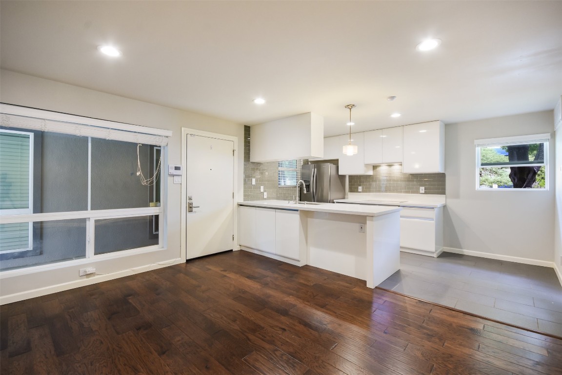 a large white kitchen with kitchen island a sink wooden floor and a refrigerator