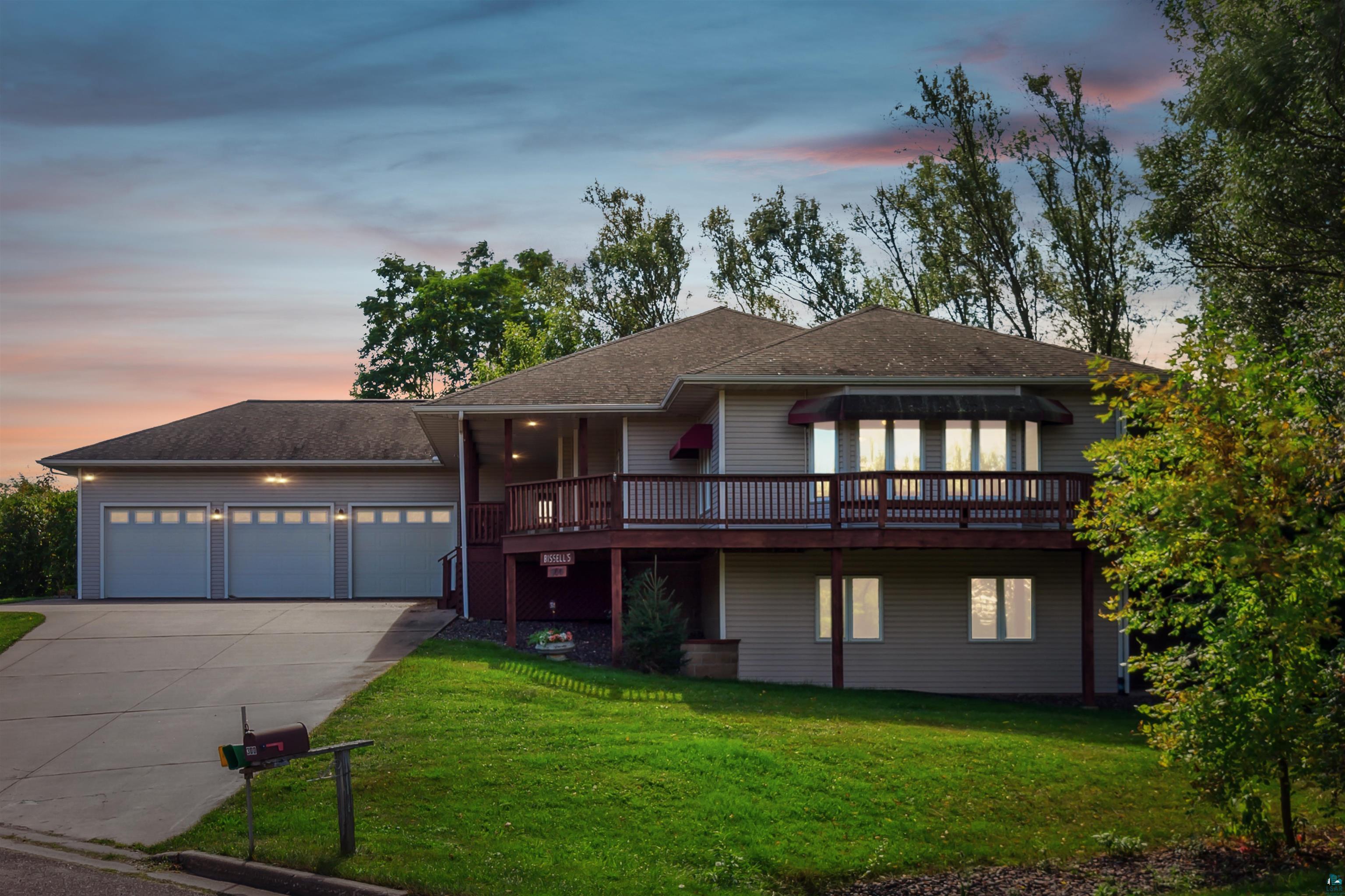 View of front of property with a garage, a deck, and a lawn