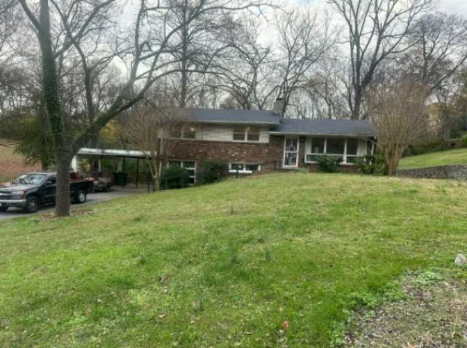 a front view of a house with a garden and trees