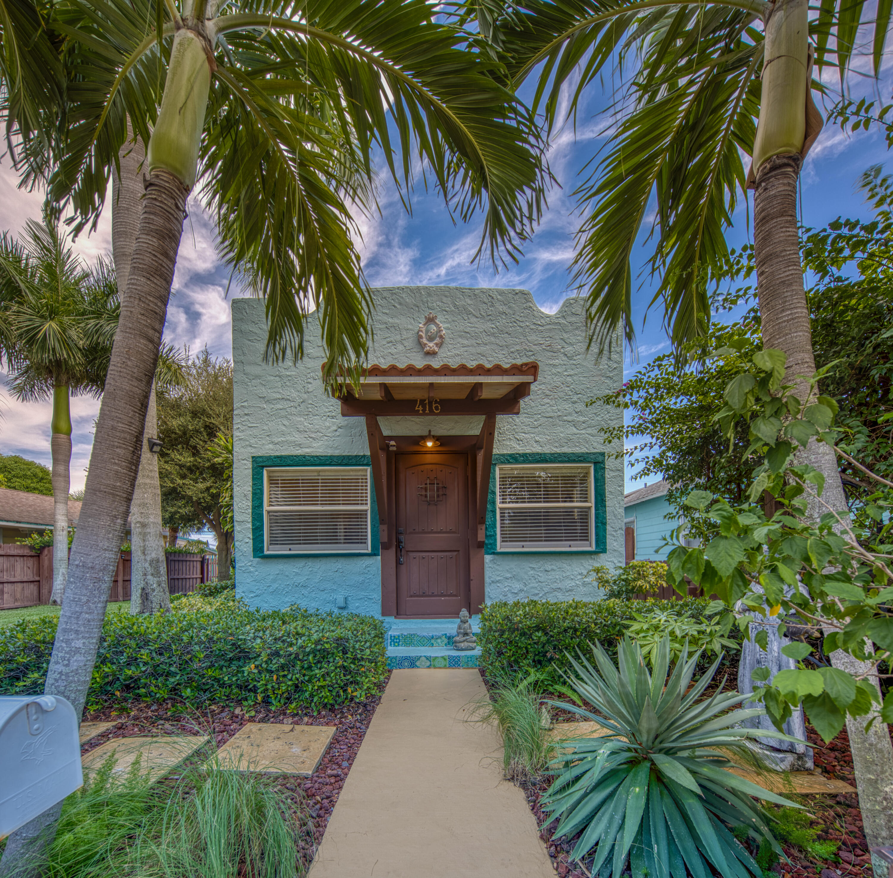 a view of a house with a small yard plants and palm trees