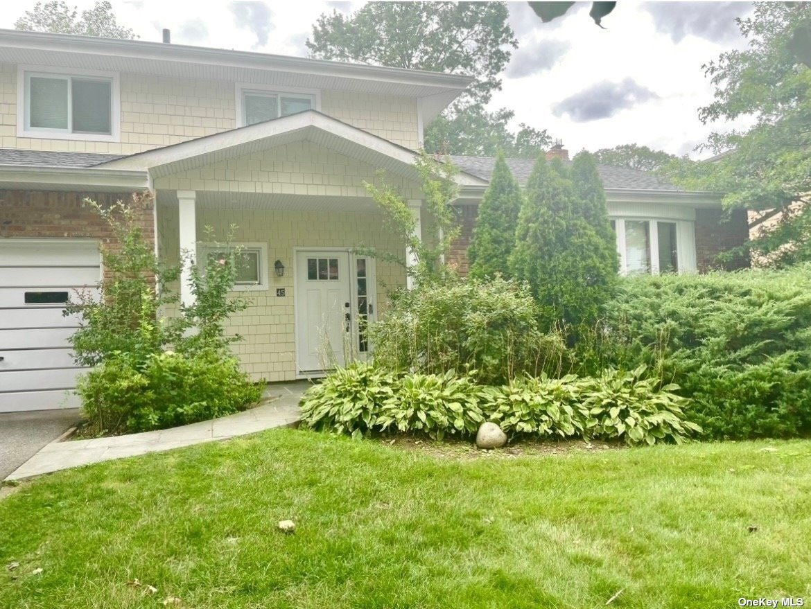 a view of a house with brick walls and a yard with plants