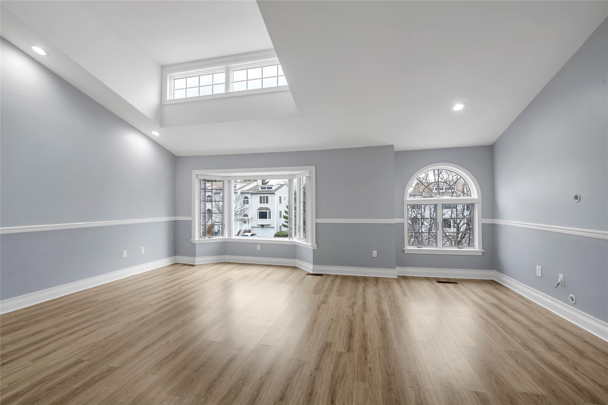 Unfurnished living room featuring a towering ceiling, light hardwood / wood-style floors, and plenty of natural light