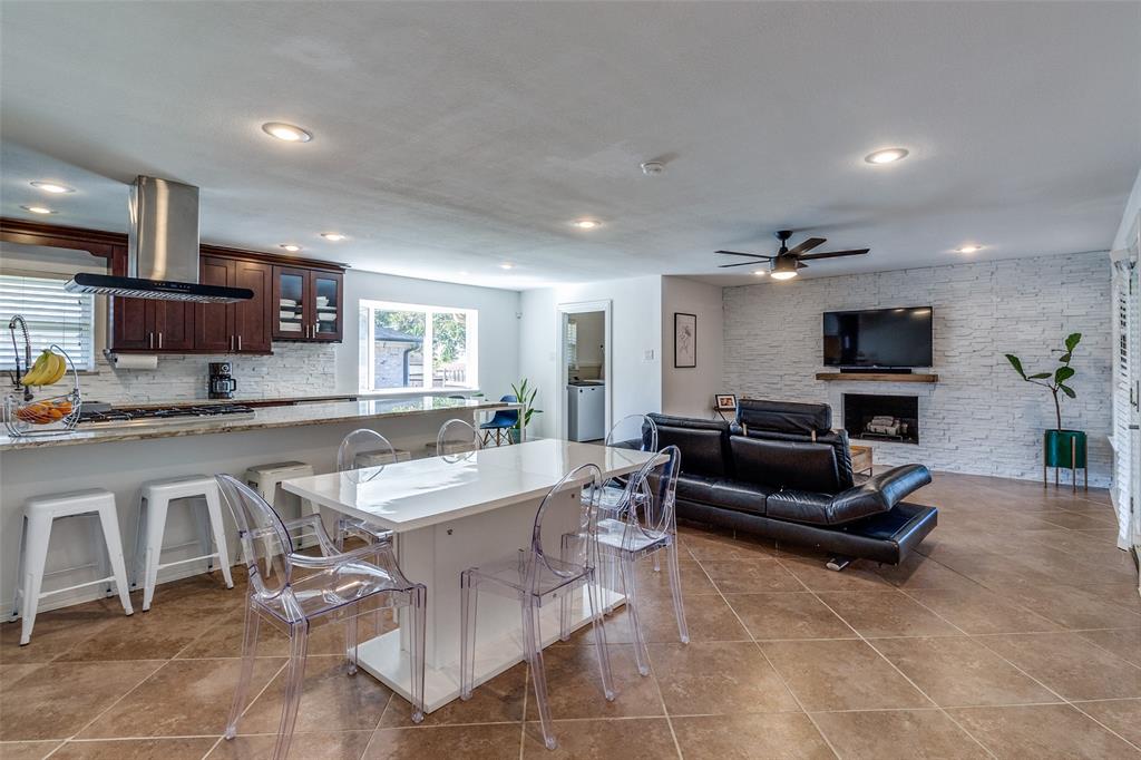 a living room with stainless steel appliances furniture a rug and a kitchen view