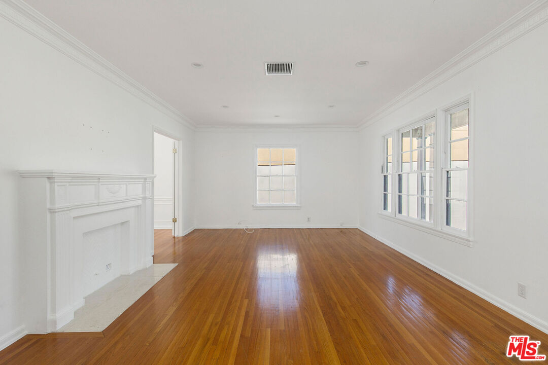 a view of an empty room with wooden floor and window