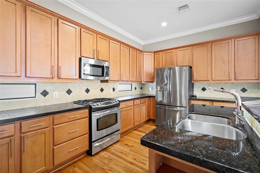 a kitchen with granite countertop a refrigerator stove top oven and sink