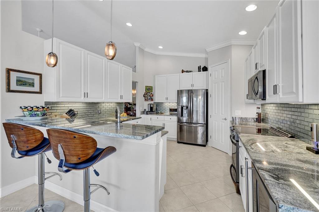 a kitchen with stainless steel appliances granite countertop a sink a stove a refrigerator cabinets and chairs