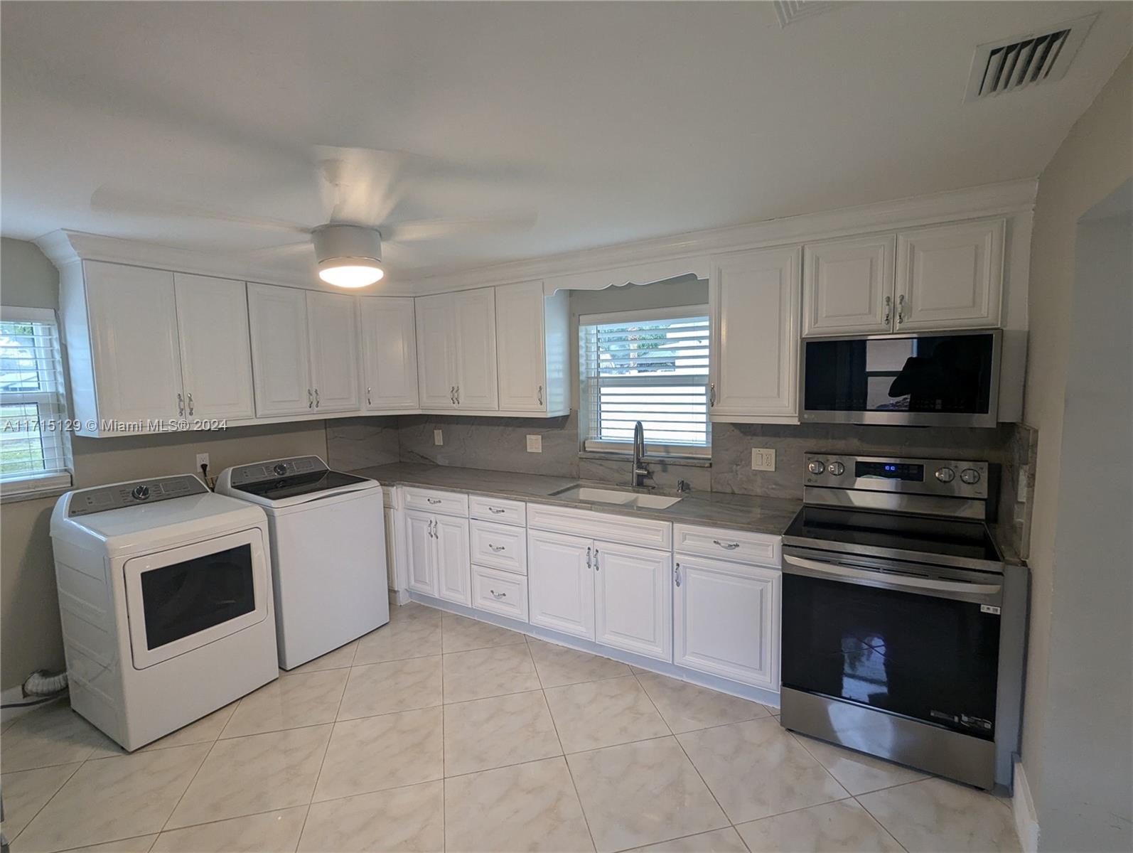 a kitchen with granite countertop a stove top oven sink and cabinets