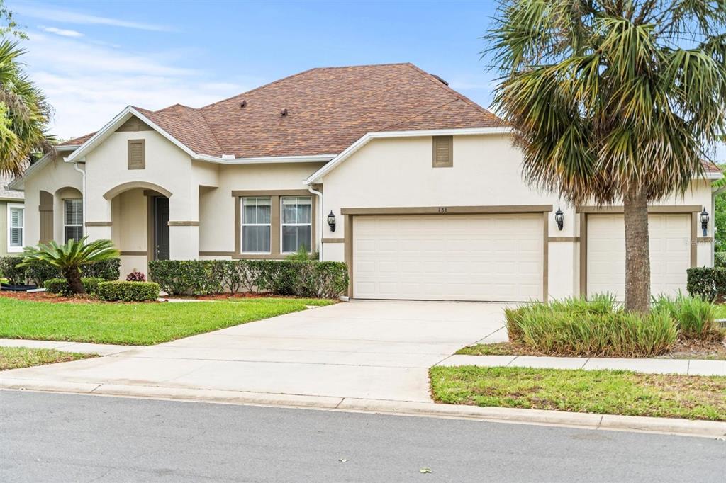 a front view of a house with a garden and palm tree