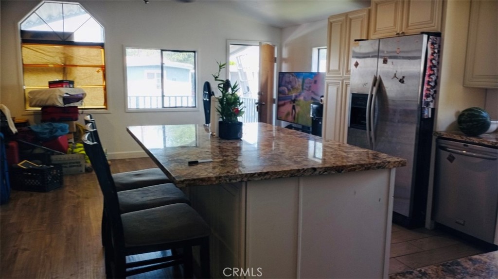 a kitchen with stainless steel appliances granite countertop a table chairs refrigerator and sink