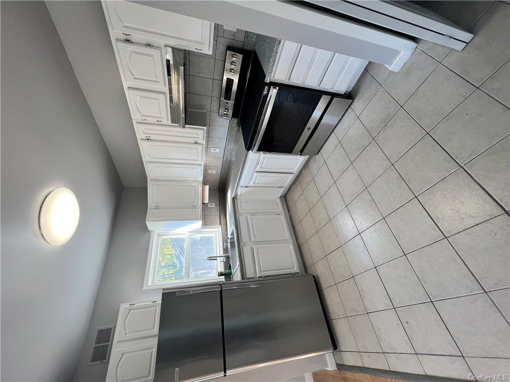 Kitchen featuring refrigerator, white cabinets, stove, and extractor fan