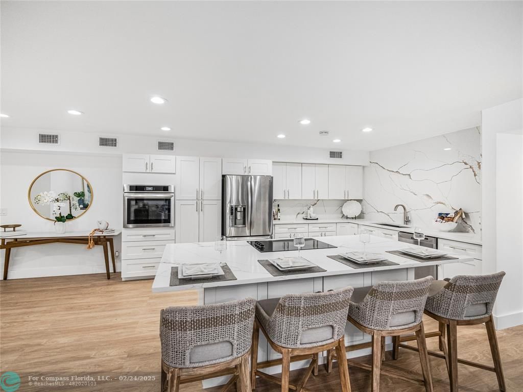 a kitchen with stainless steel appliances granite countertop a table chairs stove and refrigerator