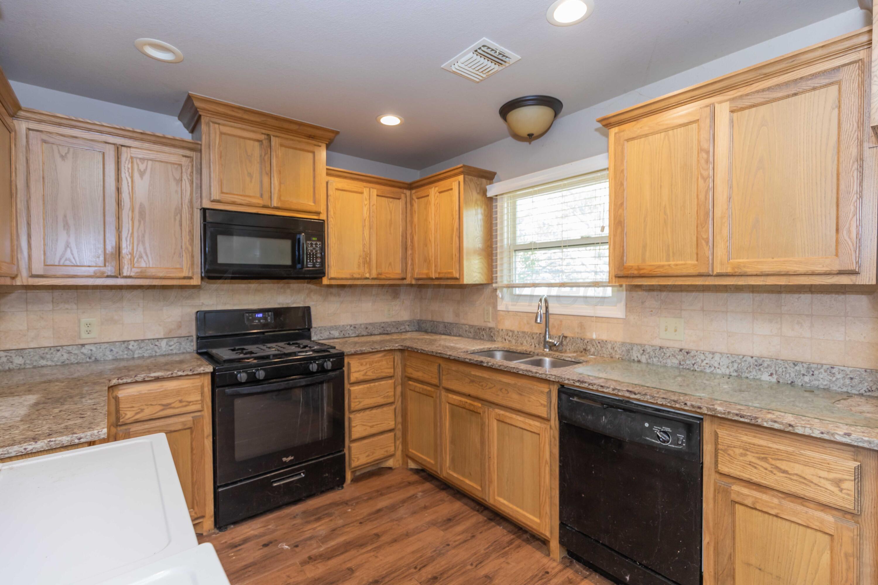 a kitchen with stainless steel appliances granite countertop white cabinets granite counter tops and a window