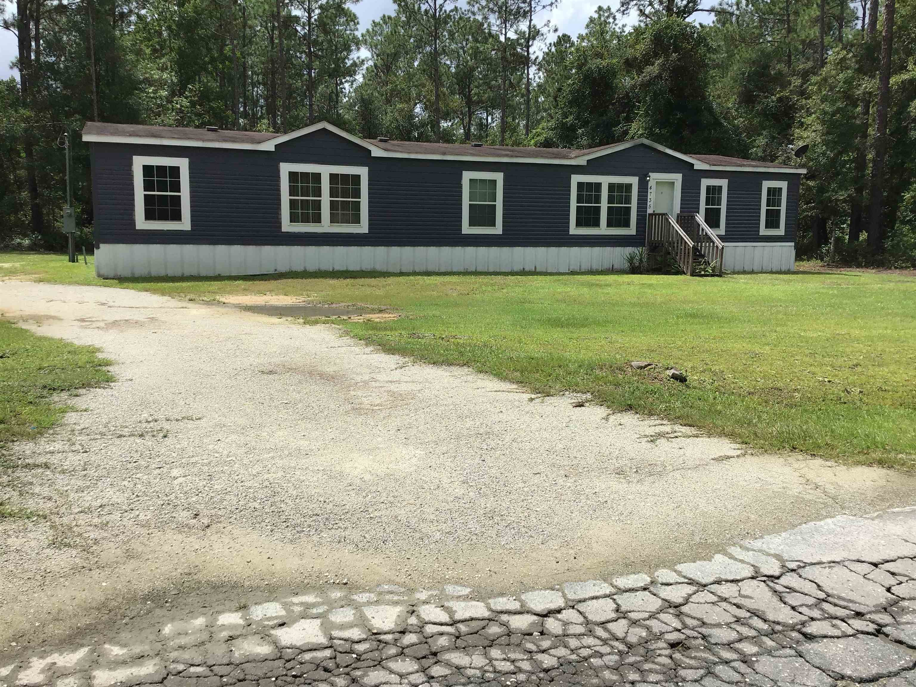 a front view of a house with yard and trees