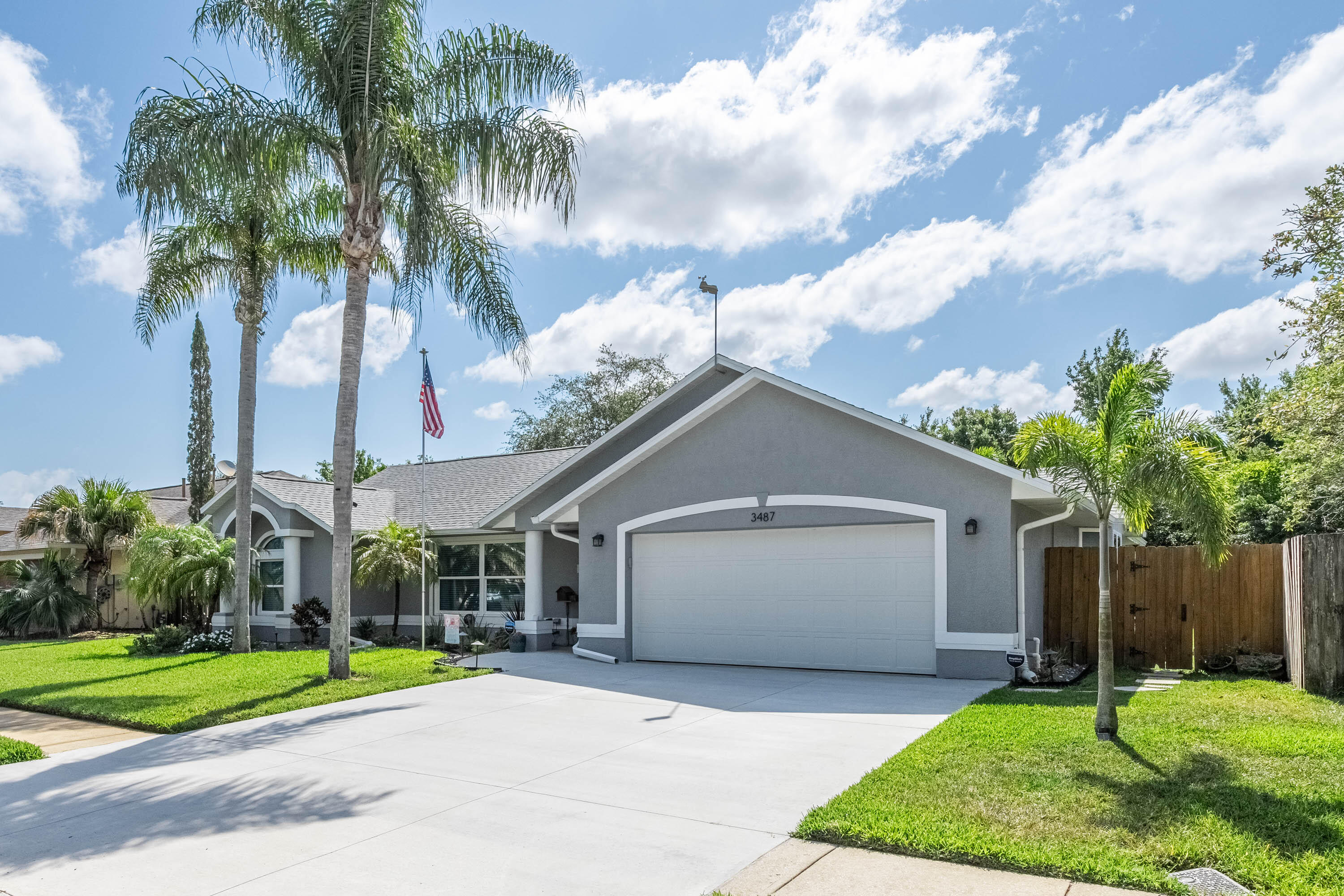 a view of a white house next to a yard with palm trees