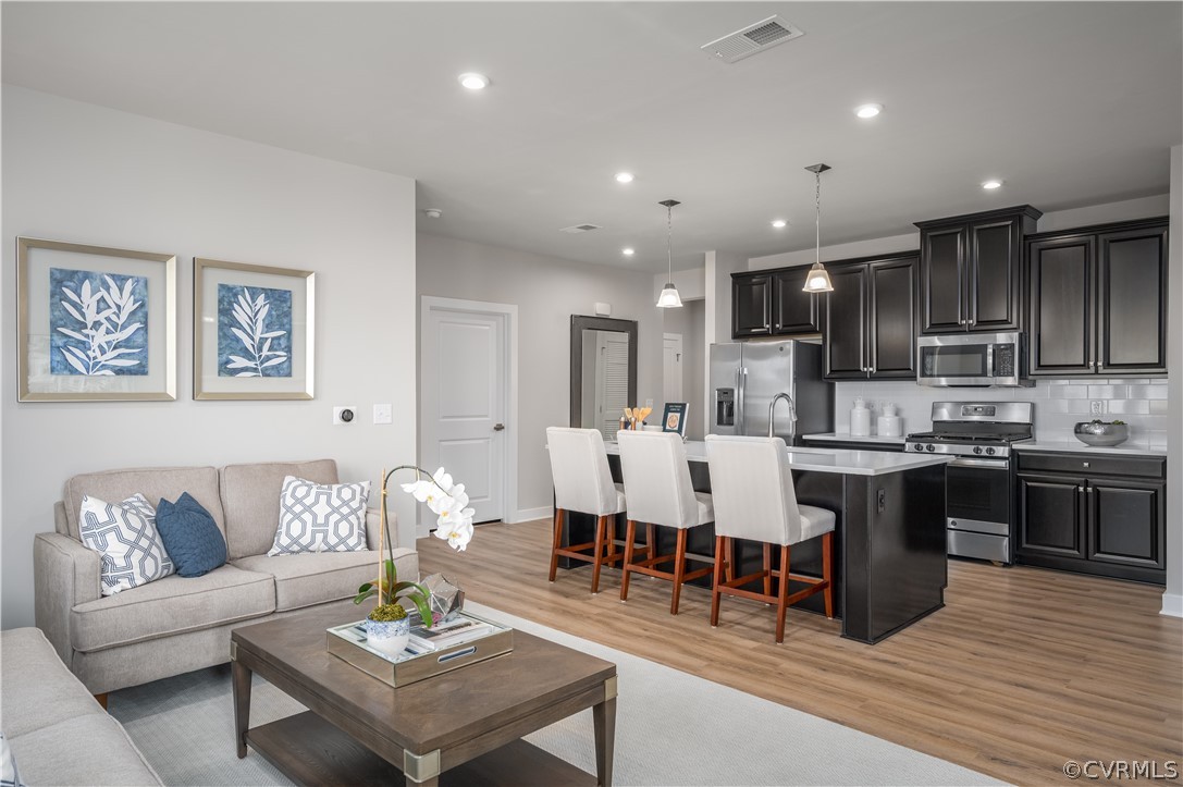 a living room with stainless steel appliances kitchen island granite countertop a couch wooden floor and kitchen view