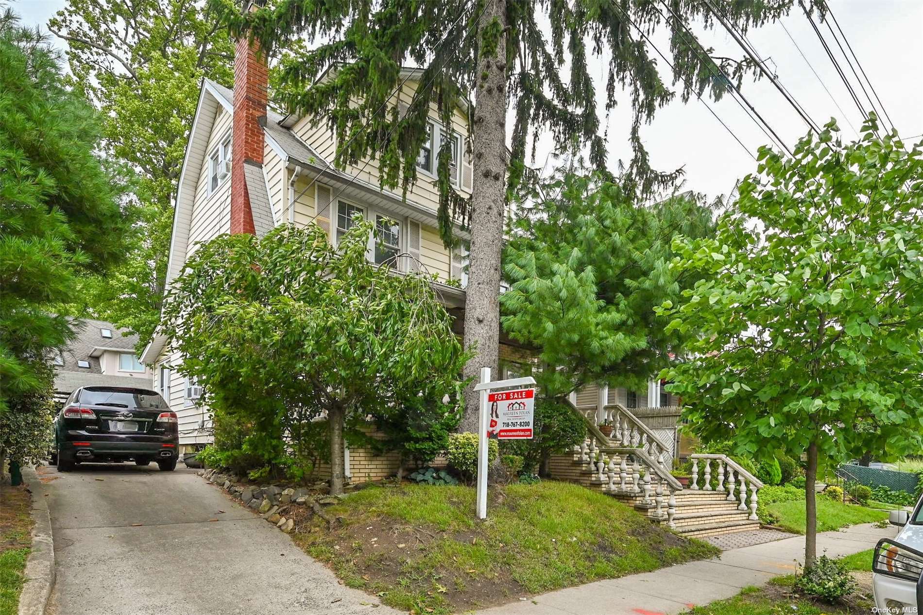 a car parked in front of a brick house with large trees