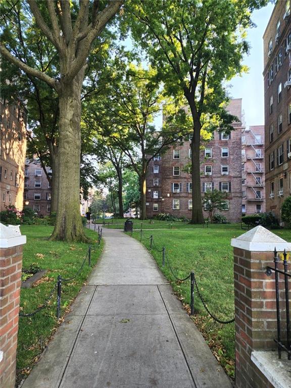 a view of a brick house next to a yard with big trees