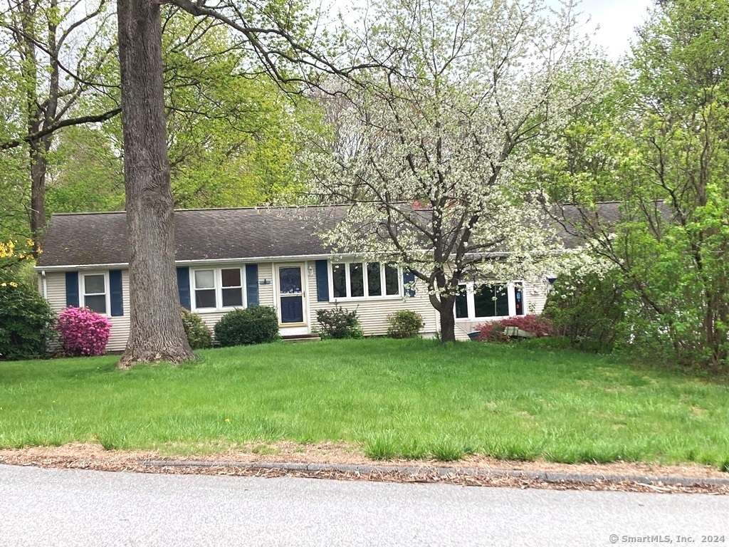 a front view of a house with a garden and trees