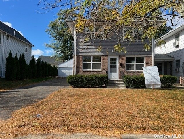 a front view of house with yard and trees in the background