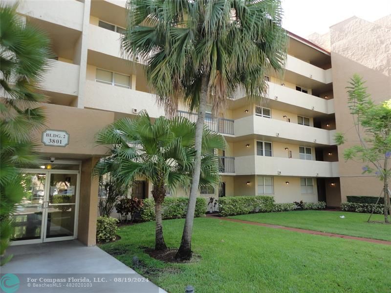 a front view of multi story residential apartment building with yard and green space