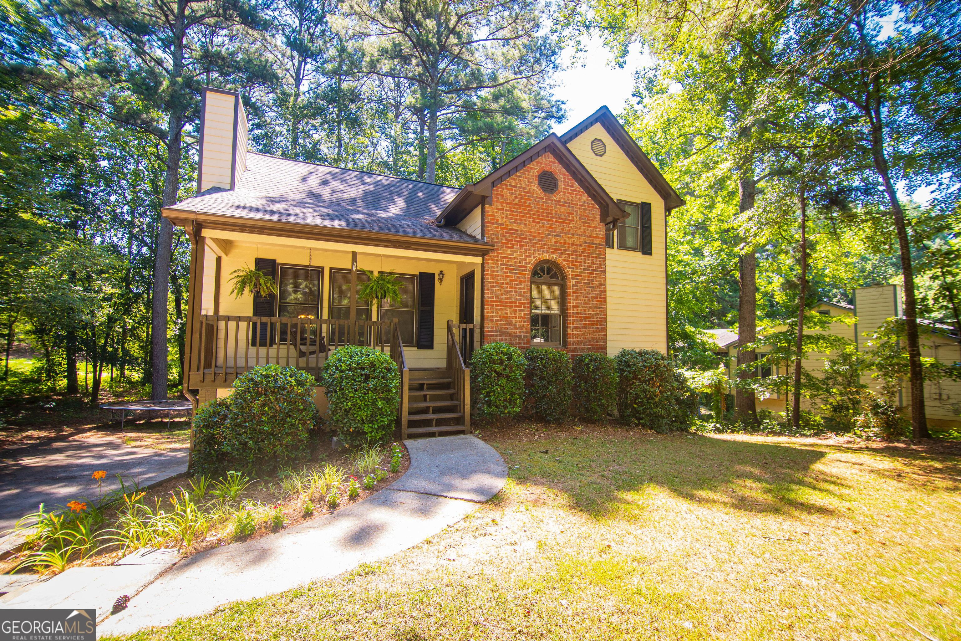 a view of a house with a small yard plants and large tree