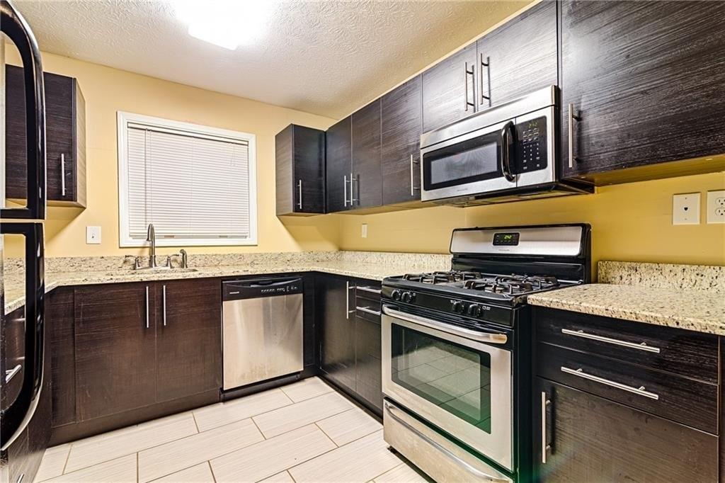 a kitchen with stainless steel appliances granite countertop a stove microwave and sink