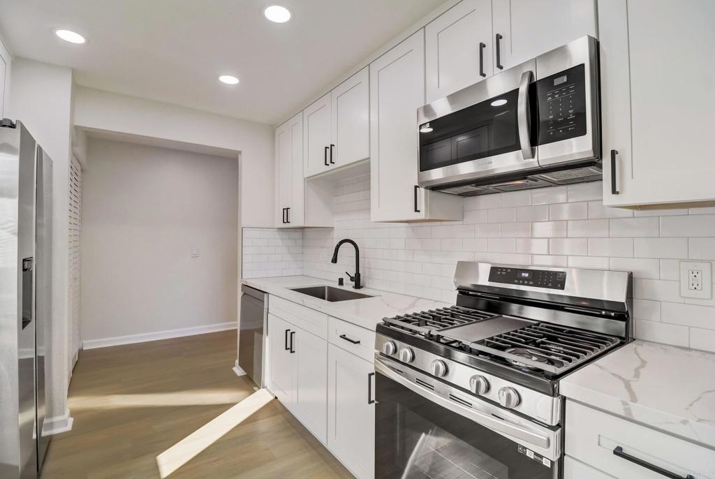 a kitchen with stainless steel appliances granite countertop white cabinets a stove top oven a sink and dishwasher