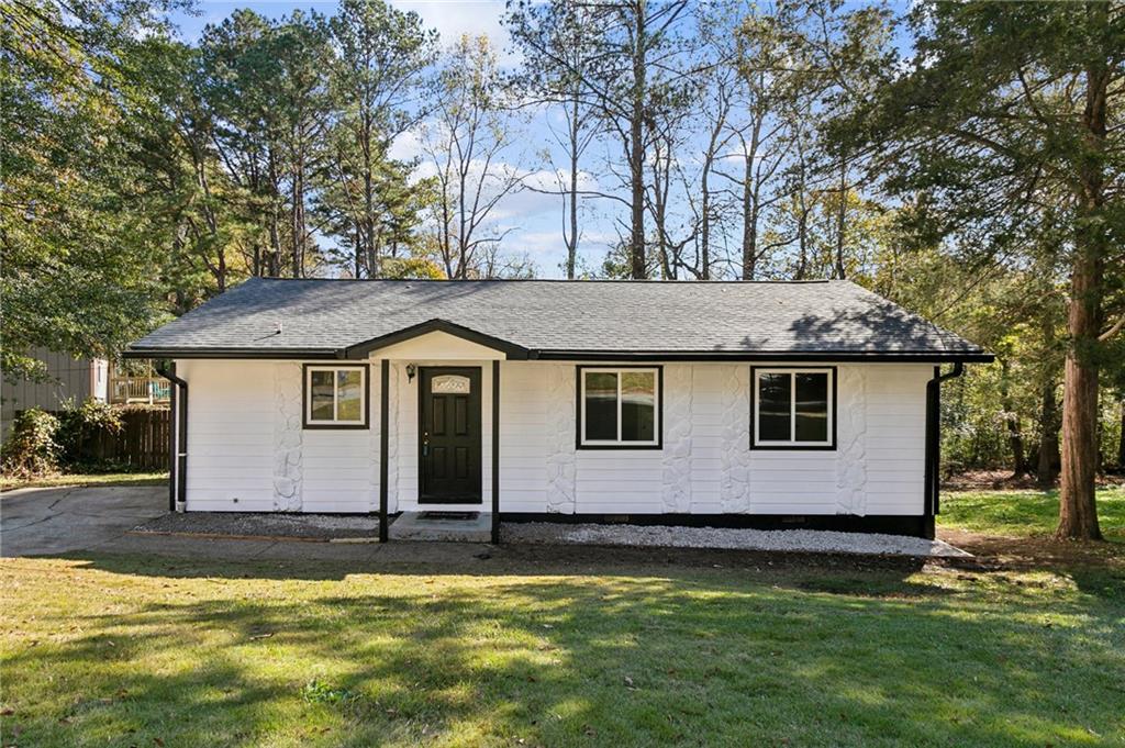 a front view of house with yard and trees in the background