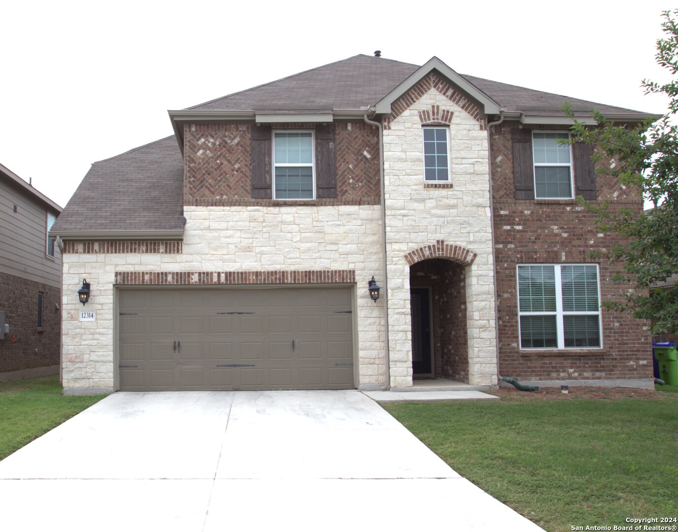 a front view of a house with a garden and garage