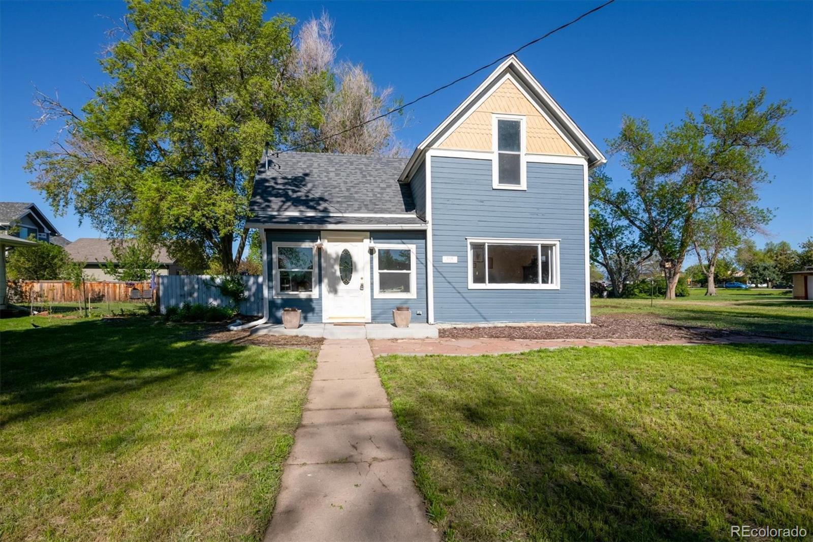 a front view of a house with a yard and trees